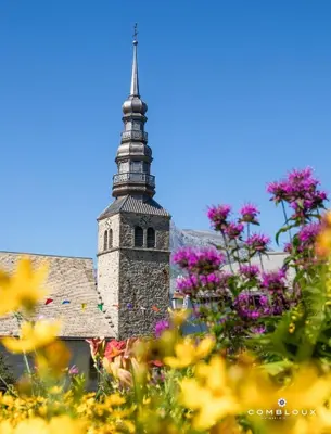 a church with a tower with a bunch of flowers at Les Ours de Combloux in Combloux