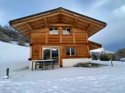 a log cabin with a table in the snow at Les Ours de Combloux in Combloux
