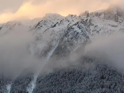 a mountain covered in snow and clouds in front of it at Chamonix sud -Le Grepon in Chamonix-Mont-Blanc