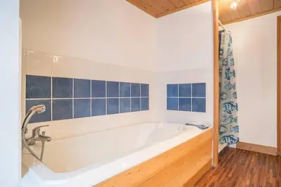 a white bath tub in a bathroom with blue tiles at Appartement spacieux proche des télécabines et du centre ville avec jardin privé in Saint-Gervais-les-Bains