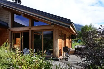 a house with a large glass door on a deck at Grand chalet Le Trappeur - Chamonix in Chamonix-Mont-Blanc