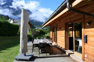 a wooden deck with a table and an umbrella at Grand chalet Le Trappeur - Chamonix in Chamonix-Mont-Blanc