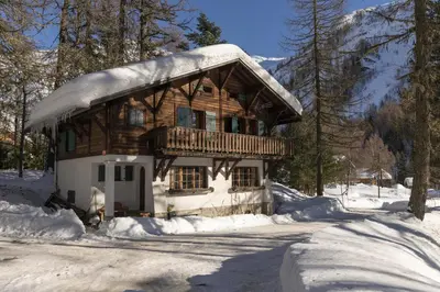 a log cabin with snow on it in the woods at Chalet Ecureuil - Happy Rentals in Chamonix-Mont-Blanc