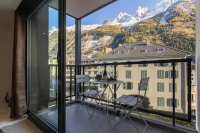 a table with wine glasses on a balcony with a mountain at Chic 1BR ideally located in the city center in Chamonix-Mont-Blanc