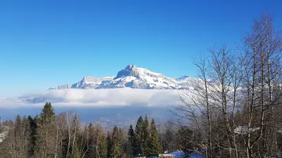 a mountain in the distance with a layer of clouds at Studio tout confort avec vue sur les sommets in Combloux