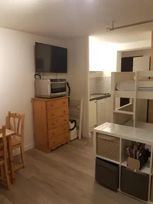 a small room with a bed and a television on a dresser at Studio tout confort avec vue sur les sommets in Combloux
