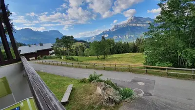 a view of a road with mountains in the background at Studio tout confort avec vue sur les sommets in Combloux