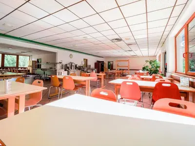 a classroom with tables and chairs and a cafeteria at Auberge de Jeunesse HI Chamonix in Chamonix-Mont-Blanc