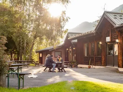 two people sitting at a picnic table outside a cabin at Auberge de Jeunesse HI Chamonix in Chamonix-Mont-Blanc