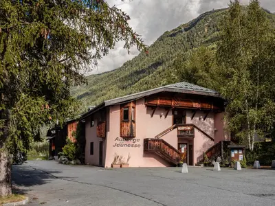 a pink building with a mountain in the background at Auberge de Jeunesse HI Chamonix in Chamonix-Mont-Blanc