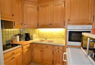 a kitchen with wooden cabinets and a sink and a microwave at Résidence du Mont-Blanc n°5Bis in Combloux