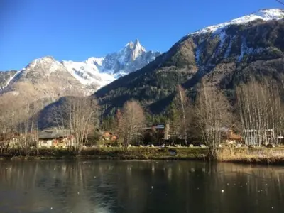 a mountain range with a house and a body of water at Chalet Champraz Studio - Free Parking in Chamonix-Mont-Blanc
