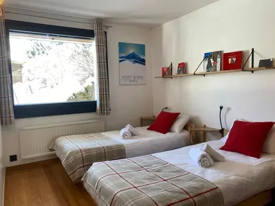 two beds sitting in a room with a window at Chambres d'hôtes - B&B - Chalet Mountain Vibes in Les Houches