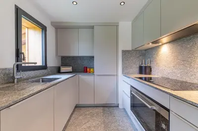 a kitchen with white cabinets and a sink at DIFY Chalet Contemporain - Les Praz de Chamonix in Chamonix-Mont-Blanc