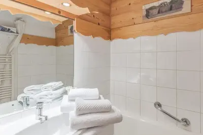 a bathroom with a tub and a sink and towels at Appartement Megève - Welkeys in Megève