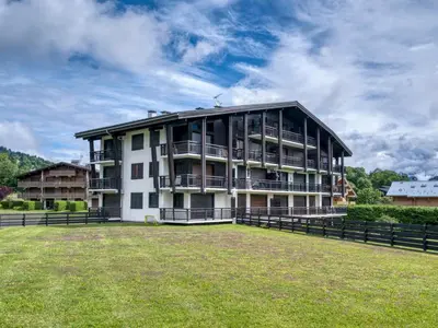 a large building with a grass field in front of it at Appart 3 pièces proche télécabine - 5 pers - Wifi - Parking - FR-1-453-229 in Megève