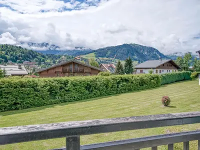 a field of grass with houses and mountains in the background at Appart 3 pièces proche télécabine - 5 pers - Wifi - Parking - FR-1-453-229 in Megève