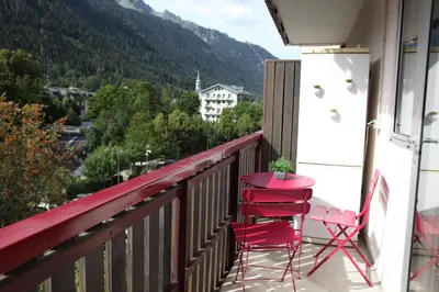 a red table and chairs on a balcony with a view at ALPINSTAR in Chamonix-Mont-Blanc