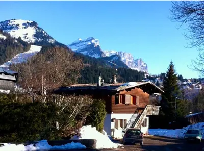 a cabin with a snow covered mountain in the background at Charmant appartement dans chalet in Les Carroz d'Araches