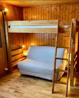 a bunk bed in a wooden room with a ladder at Charmant appartement dans chalet in Les Carroz d'Araches
