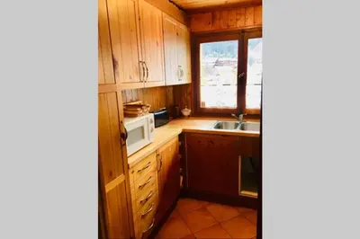 a kitchen with wooden cabinets and a sink and a window at Charmant appartement dans chalet in Les Carroz d'Araches