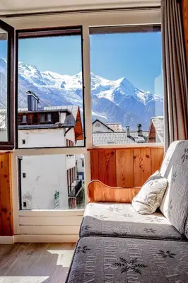 a bedroom with a large window with a view of mountains at Résidence Mummery Chamonix in Chamonix-Mont-Blanc