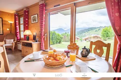a table with a basket of bread and a large window at Sur Le Feug Appt 14 in Combloux