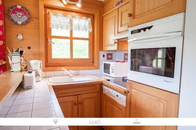 a kitchen with wooden cabinets and a white sink at Sur Le Feug Appt 14 in Combloux