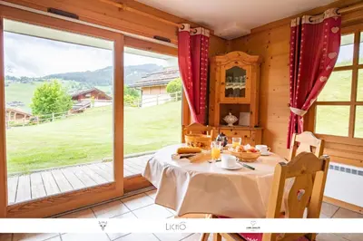 a dining room with a table and a large window at Sur Le Feug Appt 14 in Combloux