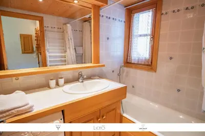 a bathroom with a sink and a tub and a mirror at Sur Le Feug Appt 14 in Combloux