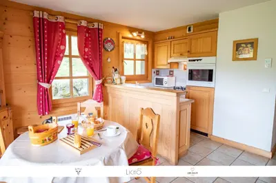 a kitchen with a table and a kitchen with wooden cabinets at Sur Le Feug Appt 14 in Combloux