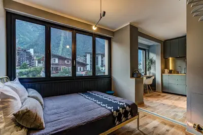a bedroom with a bed and large windows at Chamonix City Center Luxury Studio Apartment in Chamonix-Mont-Blanc
