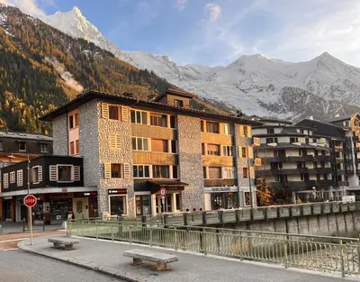 a building on a street with mountains in the background at Chamonix City Center Luxury Studio Apartment in Chamonix-Mont-Blanc
