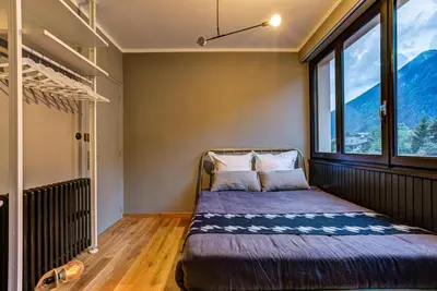 a bed in a room with a large window at Chamonix City Center Luxury Studio Apartment in Chamonix-Mont-Blanc