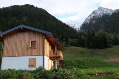 a house in a field with mountains in the background at Modern Chalet With Garden Chamonix in Chamonix-Mont-Blanc