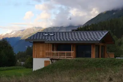a house on a hill with mountains in the background at Modern Chalet With Garden Chamonix in Chamonix-Mont-Blanc