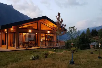 a large wooden house in a field with mountains at Modern Chalet With Garden Chamonix in Chamonix-Mont-Blanc