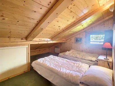 a bedroom with two beds in a wooden cabin at Appartement cosy avec mezzanine, au pied des pistes à Combloux, parking inclus - FR-1-560-25 in Combloux