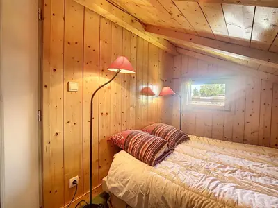 a bedroom with wooden walls and a bed with two lamps at Appartement cosy avec mezzanine, au pied des pistes à Combloux, parking inclus - FR-1-560-25 in Combloux
