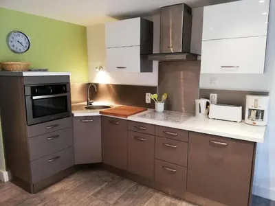 a kitchen with white cabinets and a clock on the wall at Residence Cassiopee - maeva Home in Flaine