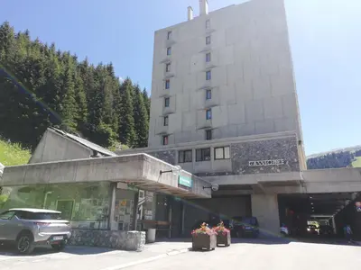 a building with a car parked in a parking lot at Residence Cassiopee - maeva Home in Flaine