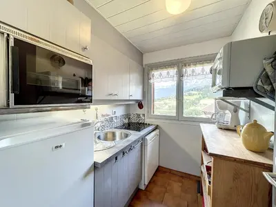 a kitchen with white cabinets and a sink and a window at Appartement cosy à Combloux avec parking et cheminée - FR-1-560-9 in Combloux