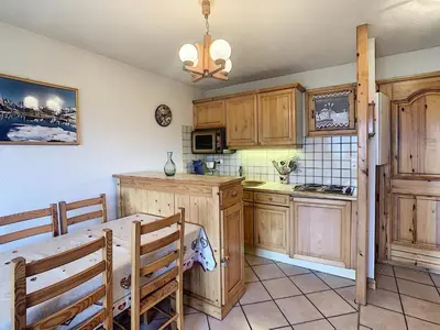a kitchen with wooden cabinets and a table at 3 pièces standing proche centre - Balcon Expo Est - FR-1-560-5 in Combloux