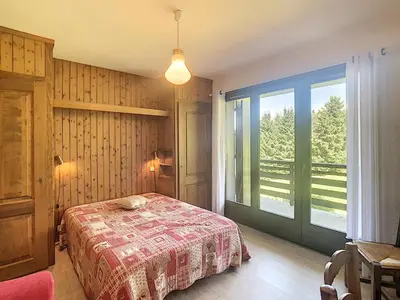a bedroom with a bed and a large window at Appartement cosy 3 pièces avec cheminée et parking couvert au pied des pistes à Combloux - FR-1-560-18 in Combloux