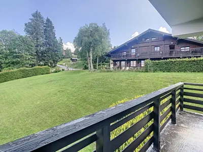 a house with a fence in front of a yard at Appartement cosy 3 pièces avec cheminée et parking couvert au pied des pistes à Combloux - FR-1-560-18 in Combloux