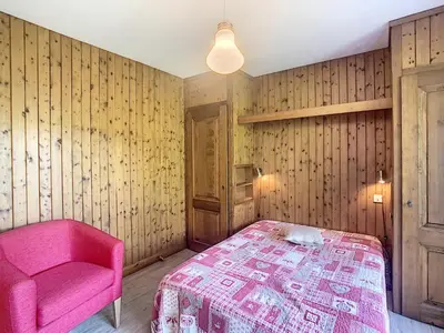 a bedroom with a pink bed and a chair at Appartement cosy 3 pièces avec cheminée et parking couvert au pied des pistes à Combloux - FR-1-560-18 in Combloux