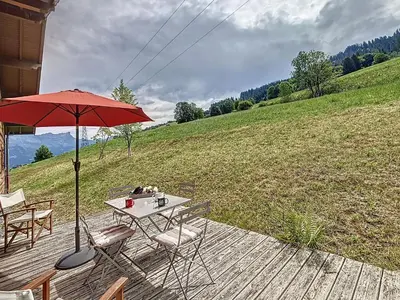 a table and chairs on a deck with an umbrella at Demi-chalet duplex proche télécabine avec WiFi - FR-1-560-6 in Combloux