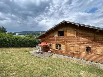 a wooden house with a deck in a field at Demi-chalet duplex proche télécabine avec WiFi - FR-1-560-6 in Combloux