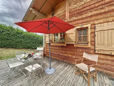 a patio with a table and chairs and a red umbrella at Demi-chalet duplex proche télécabine avec WiFi - FR-1-560-6 in Combloux