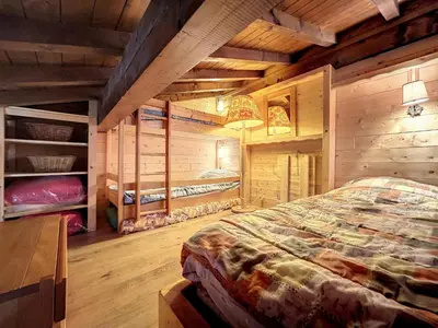 a bedroom with a bed in a room with wooden walls at Charmant duplex près du téléski du Bouchet, idéal pour famille - FR-1-560-11 in Combloux